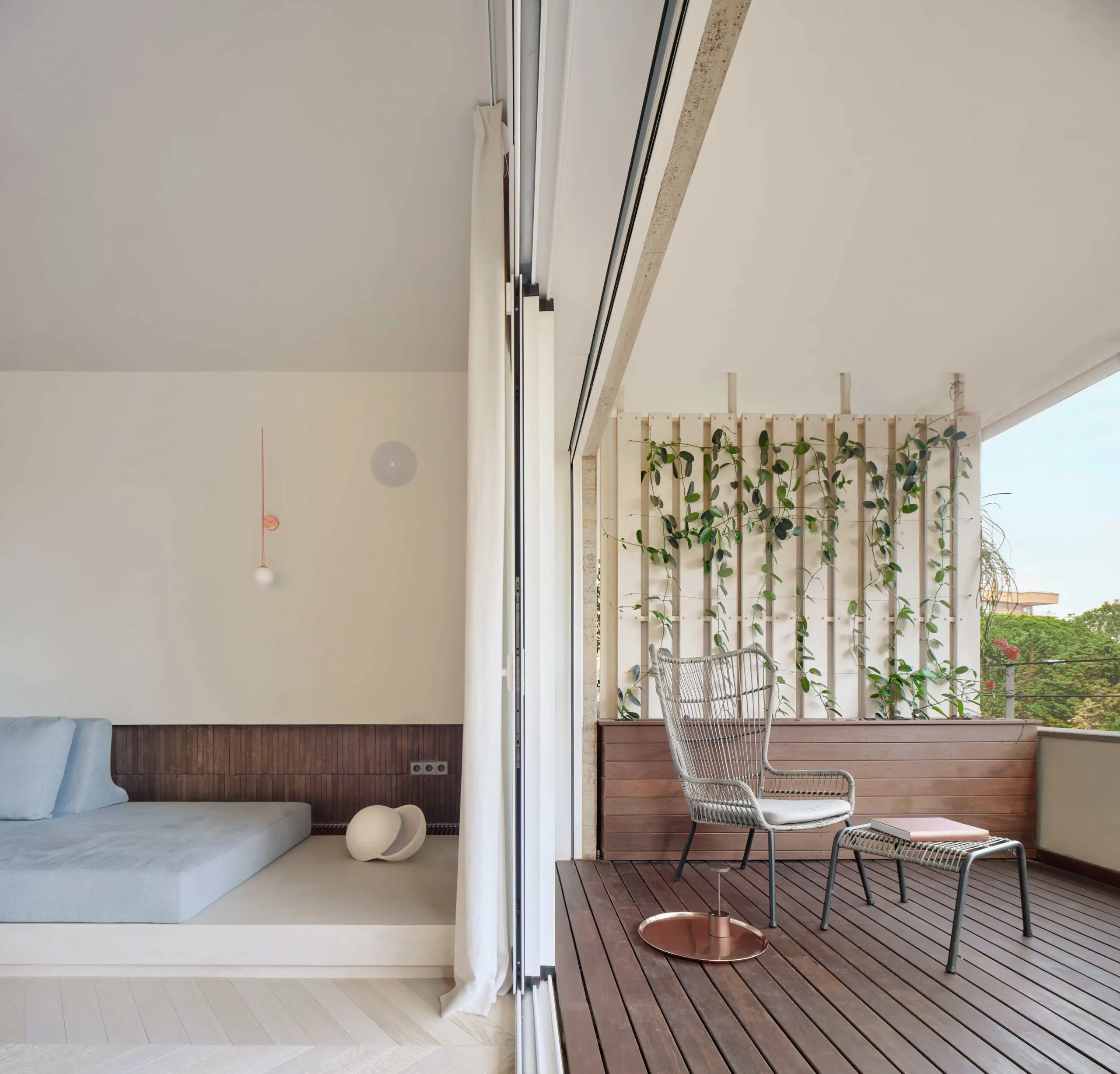 Balcony and interior lounge with built-in sofa and wooden flooring by Cometa Architects