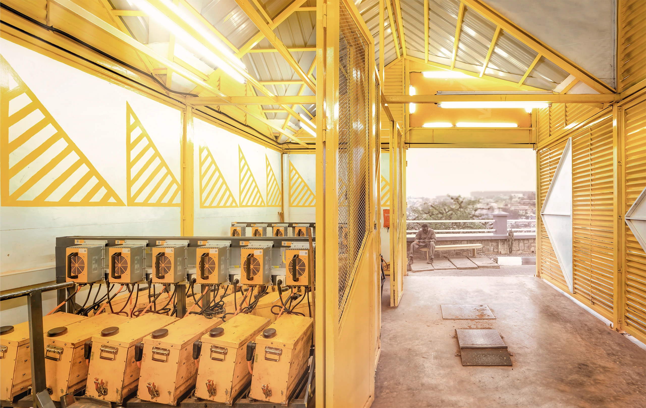 Yellow modular battery swap station with motorcycle driver arriving in Kigali