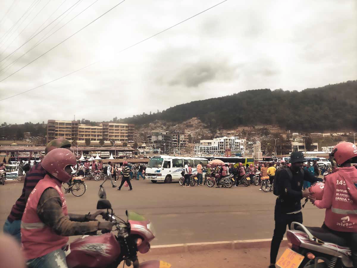 Mototaxis circulating on a winding road in Kigali with colorful urban buildings