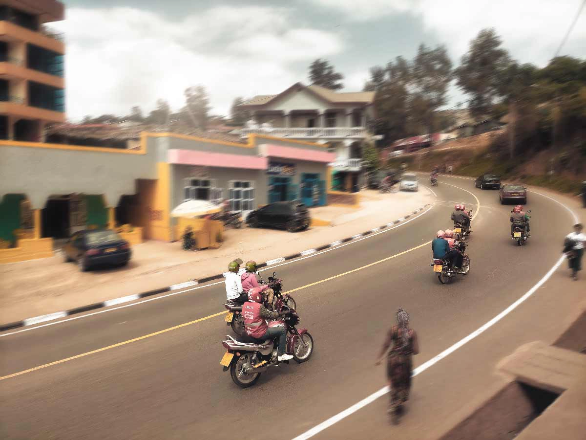 Mototaxis, buses, and riders gathering in a busy Kigali transport terminal