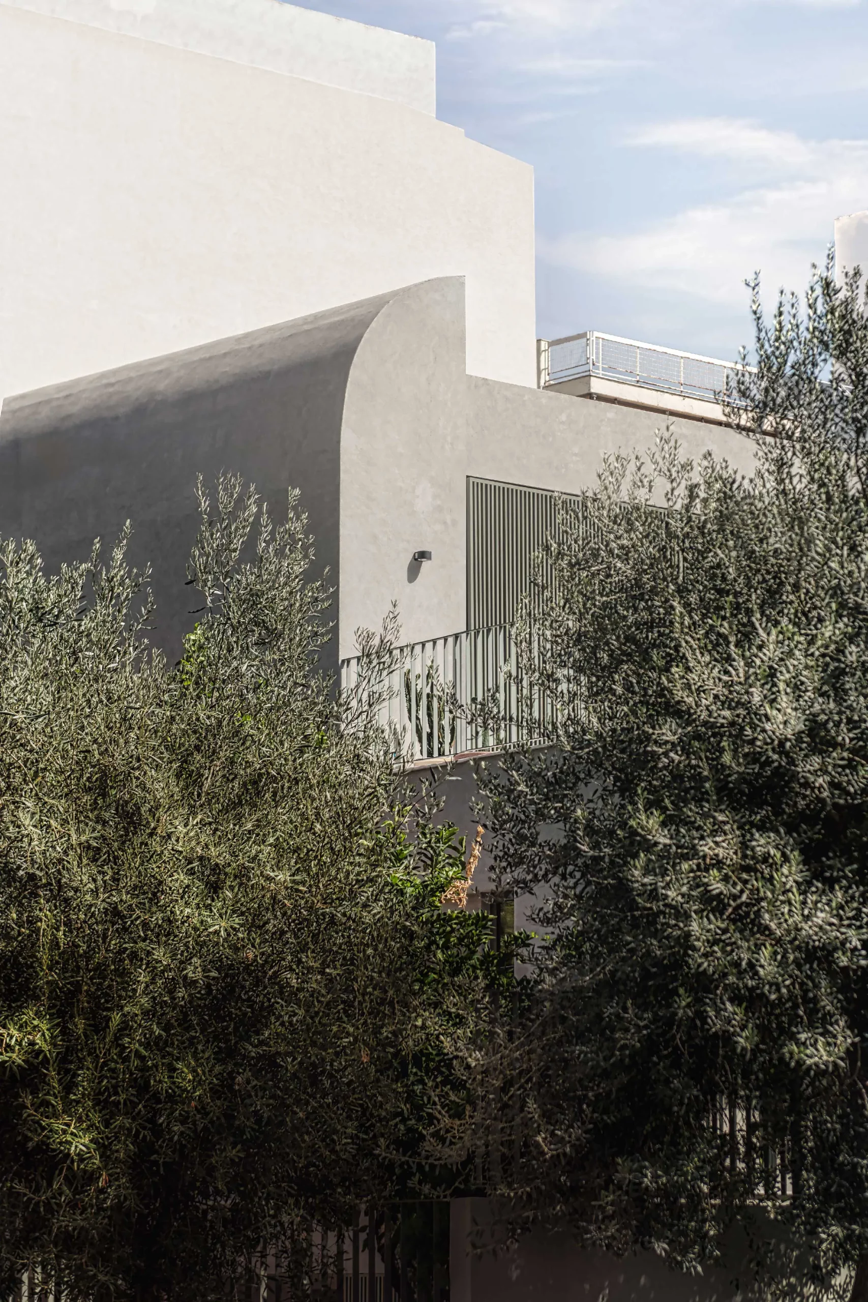 Terrace of Casa D by Cometa Architects in Athens featuring terrazzo flooring, green metal chairs, and minimalist facade with vertical shutters.