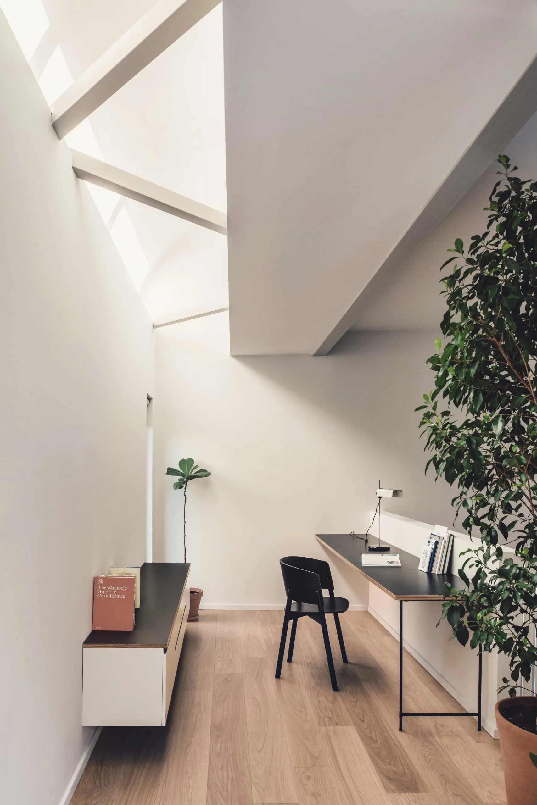 Study area of Casa D by Cometa Architects in Athens with a minimalist desk, wooden floor, and natural light from a vaulted ceiling.
