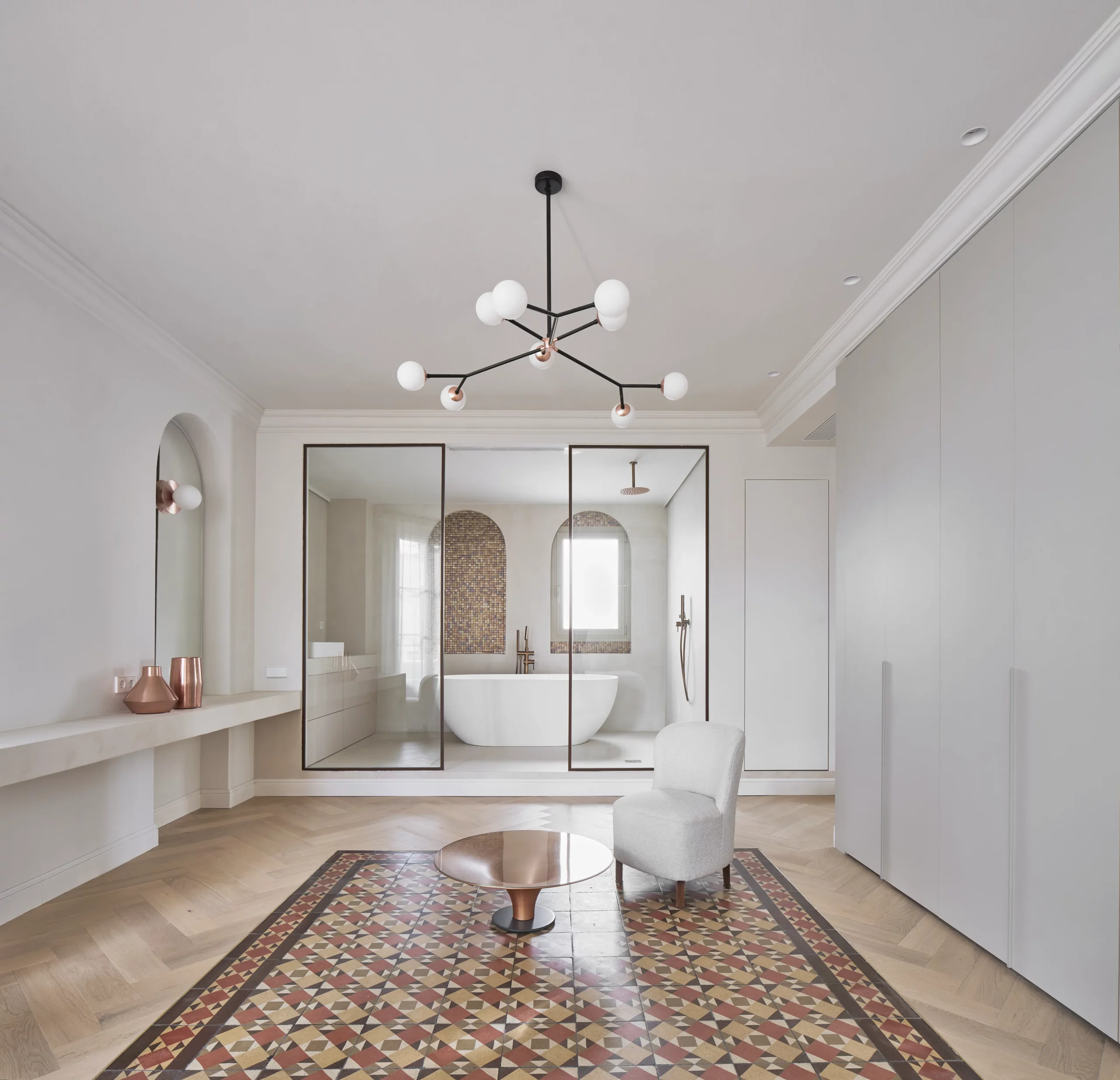 Contemporary en-suite bathroom with freestanding tub, mosaic tiles, and restored hydraulic tiles in a Barcelona apartment.