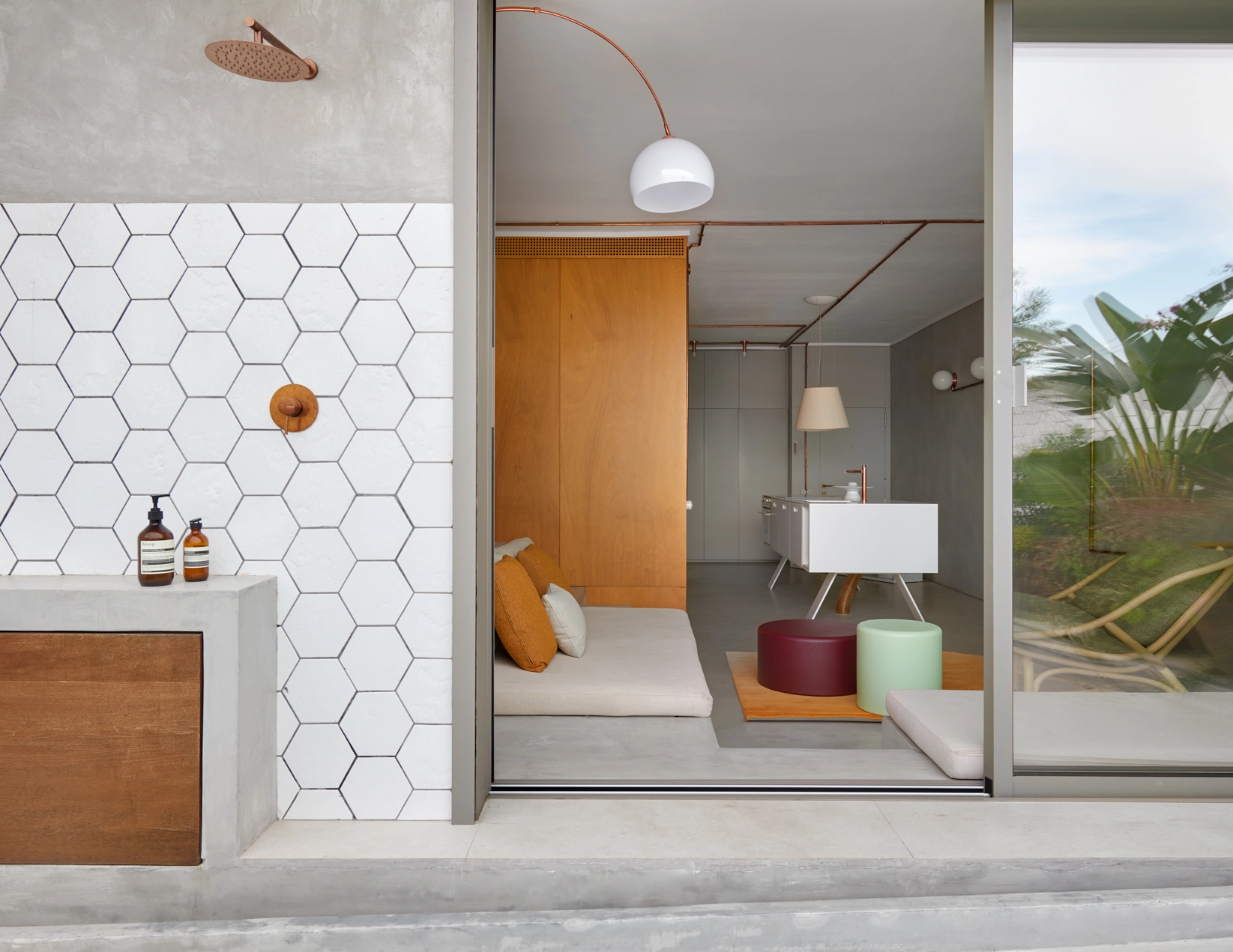 Interior view of Marina Apartment with outdoor shower, white hexagonal tiles, and copper details by Cometa Architects in Barcelona, featured in Arquitectura y Diseño magazine