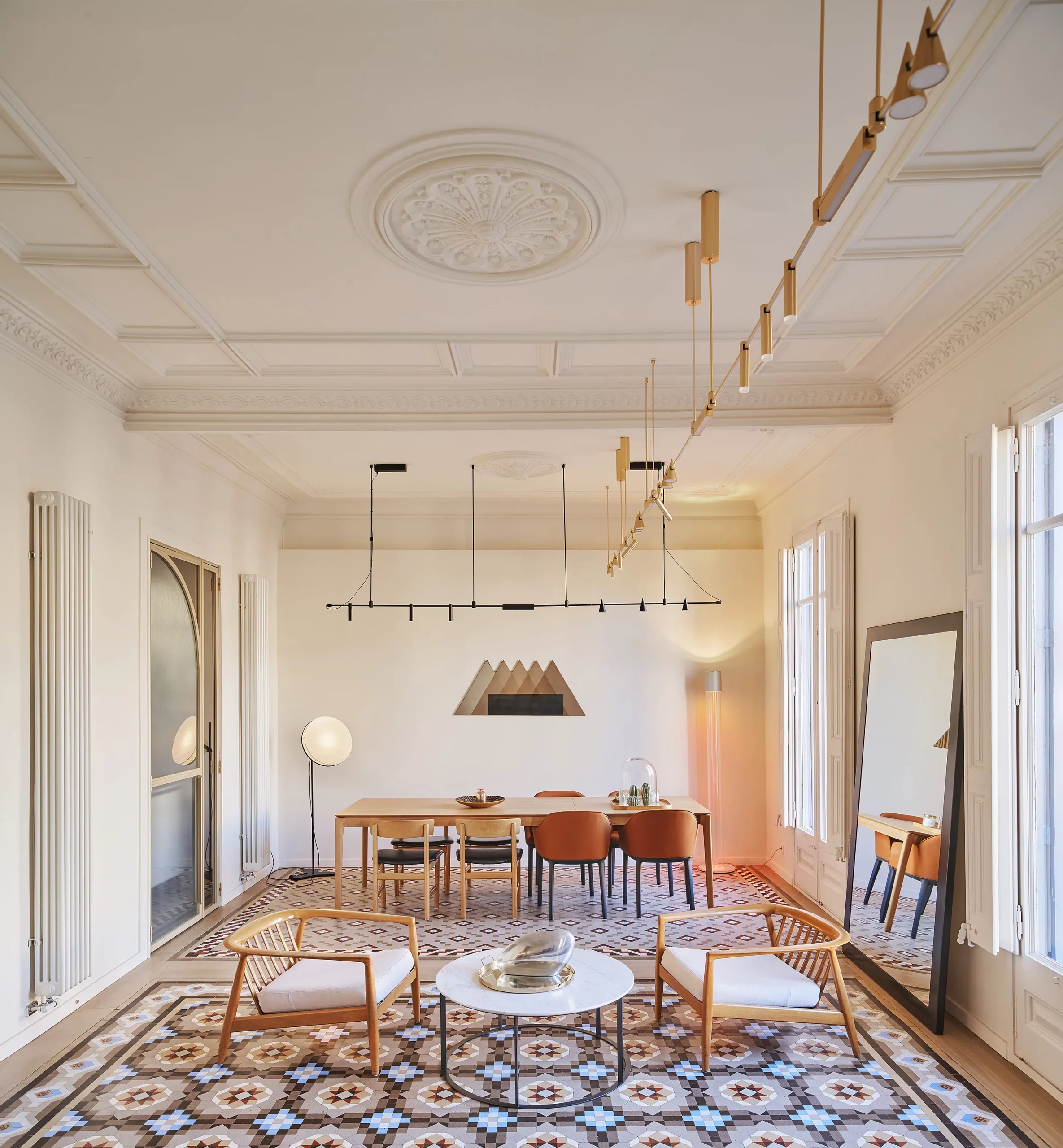 Dining room with brass suspension lighting and hydraulic tile flooring designed by Cometa Architects in Barcelona.
