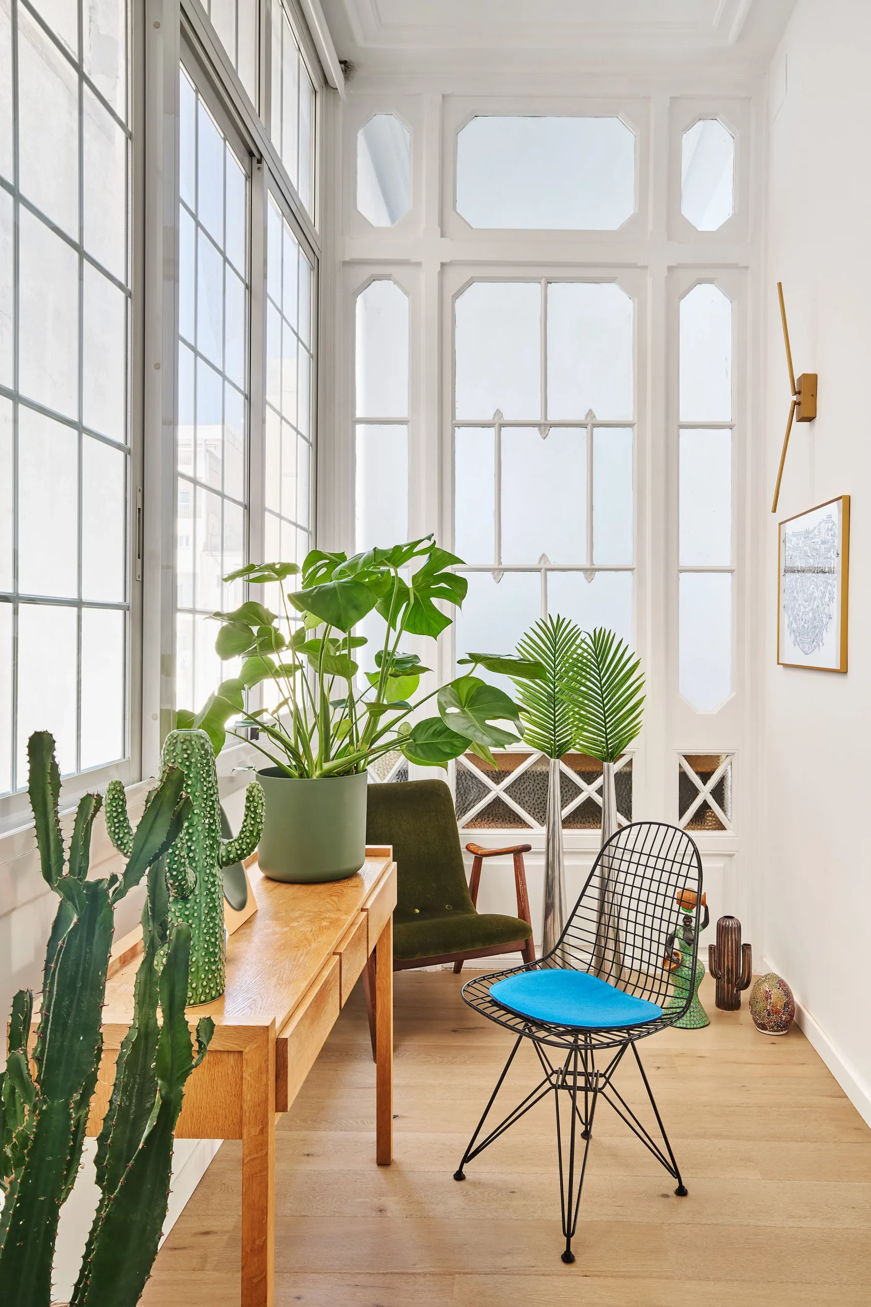 Light-filled gallery with vintage desk, plants, and modernist windows designed by Cometa Architects in Barcelona.
