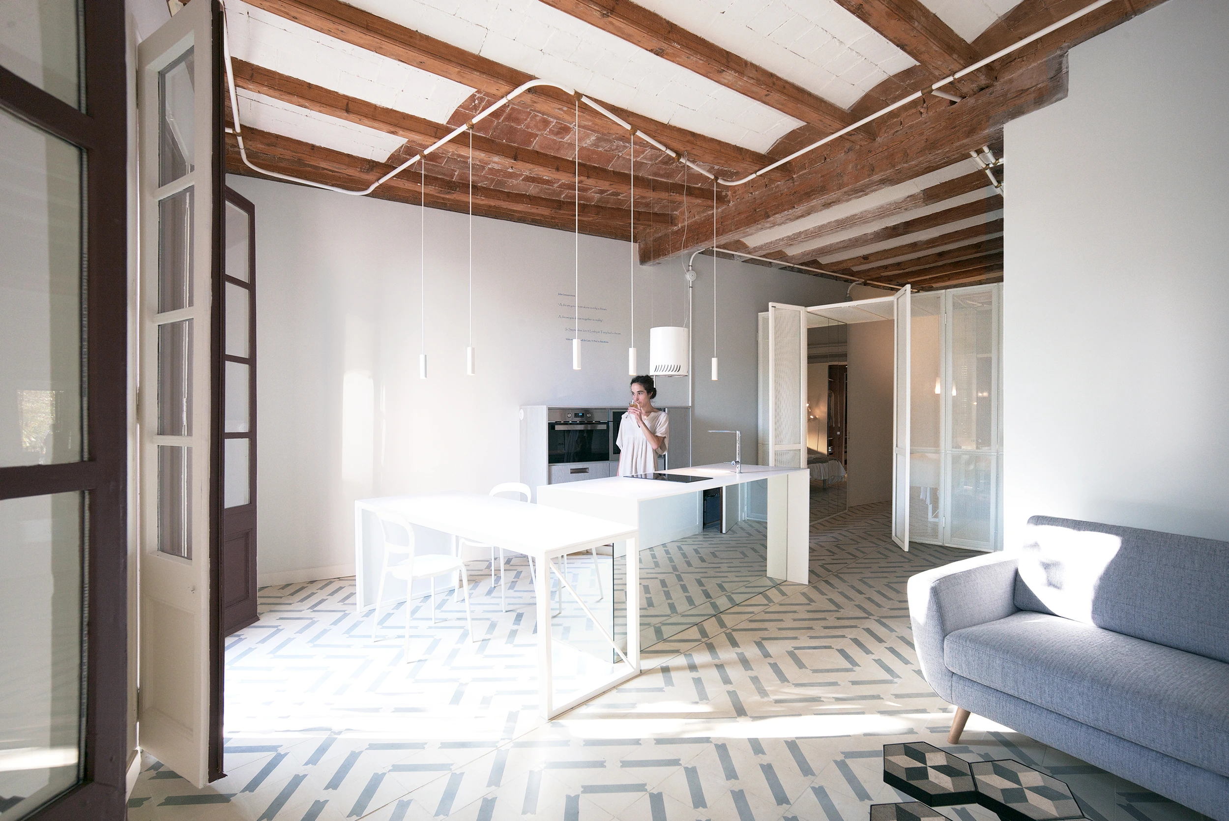 Open-plan Barcelona kitchen with mirror table, pendant lighting, and Catalan ceiling by Cometa Architects