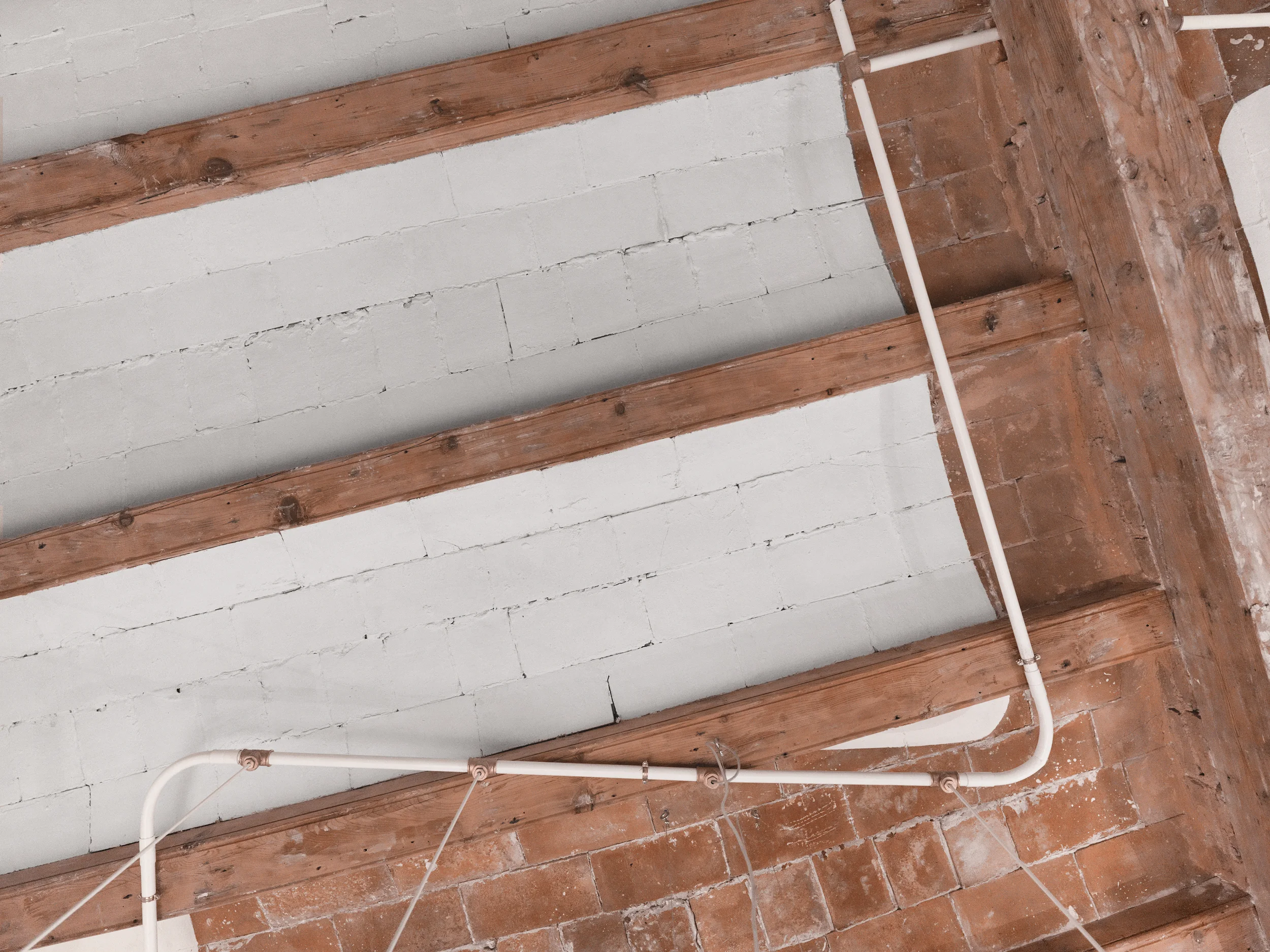 Detail of restored Catalan vaulted ceiling with exposed brick and white electrical conduits in The Lightslice apartment by Cometa Architects