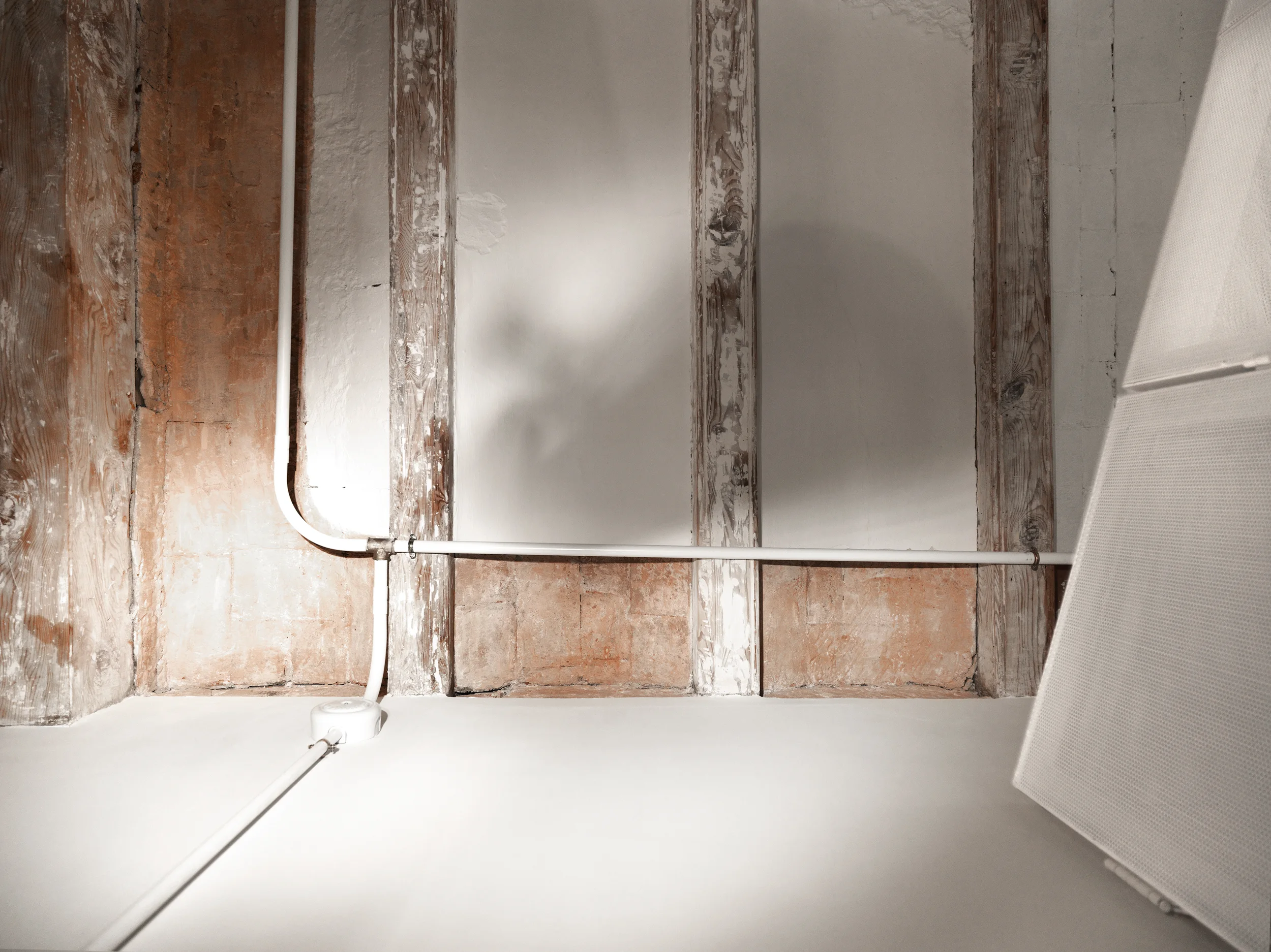 White electrical conduits crossing restored wooden beams and terracotta ceiling in The Lightslice apartment by Cometa Architects