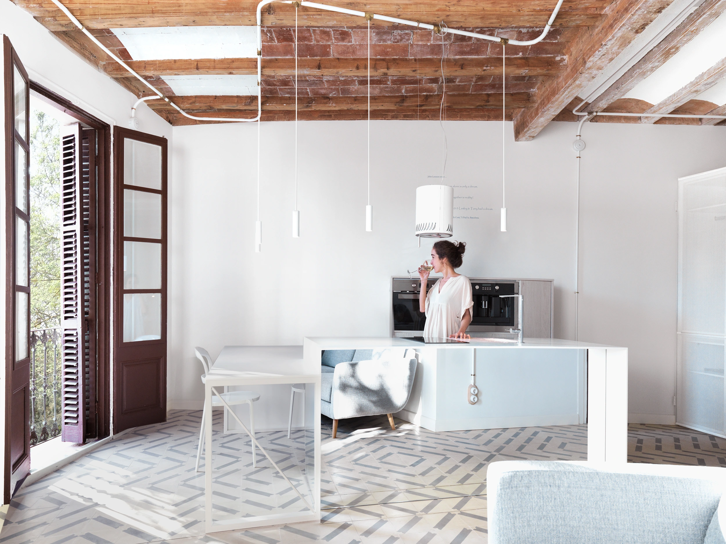 Open kitchen and dining area with balcony light and wooden beams in The Lightslice apartment by Cometa Architects