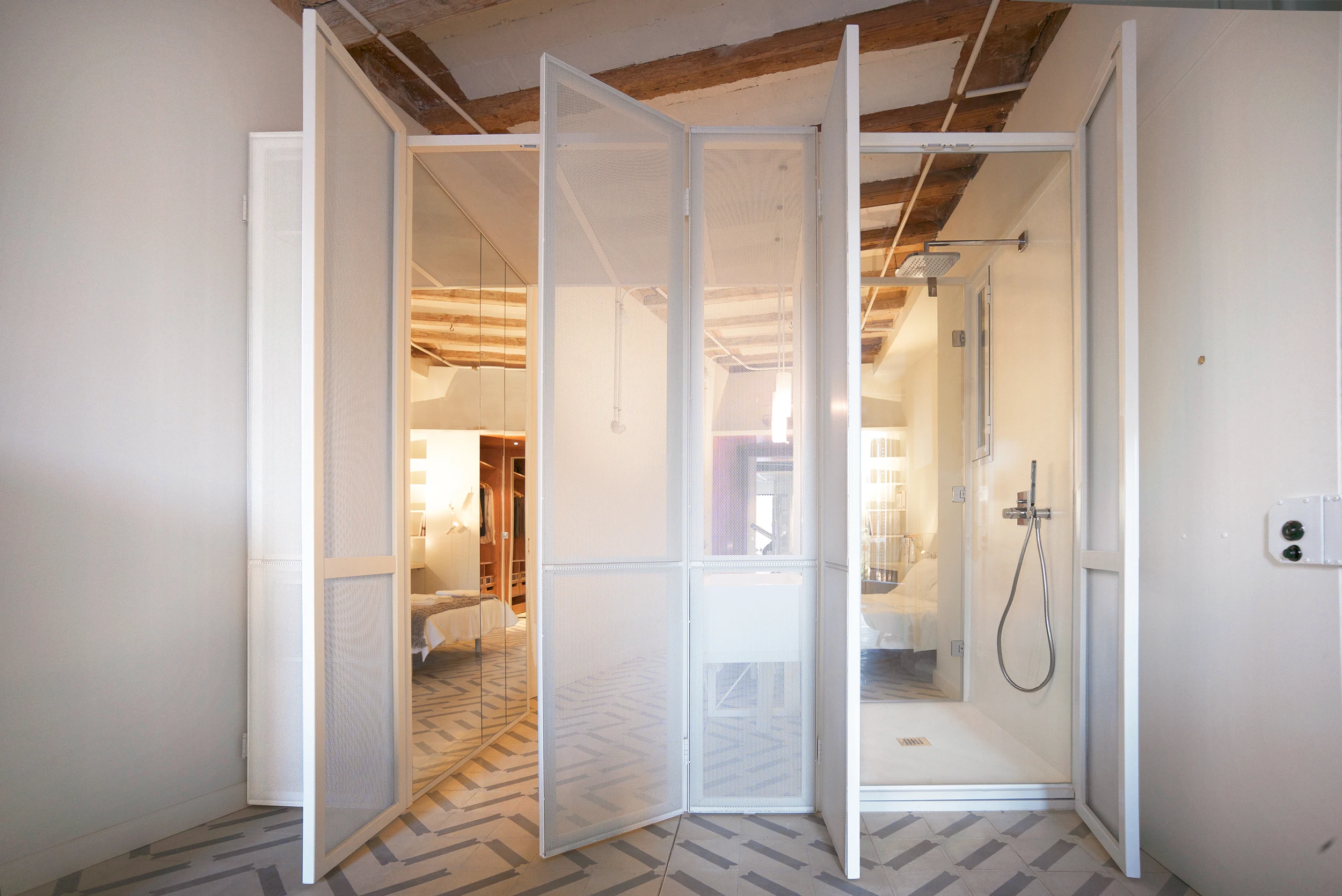 Foldable perforated bathroom screen open to reveal shower and bedroom in The Lightslice apartment by Cometa Architects