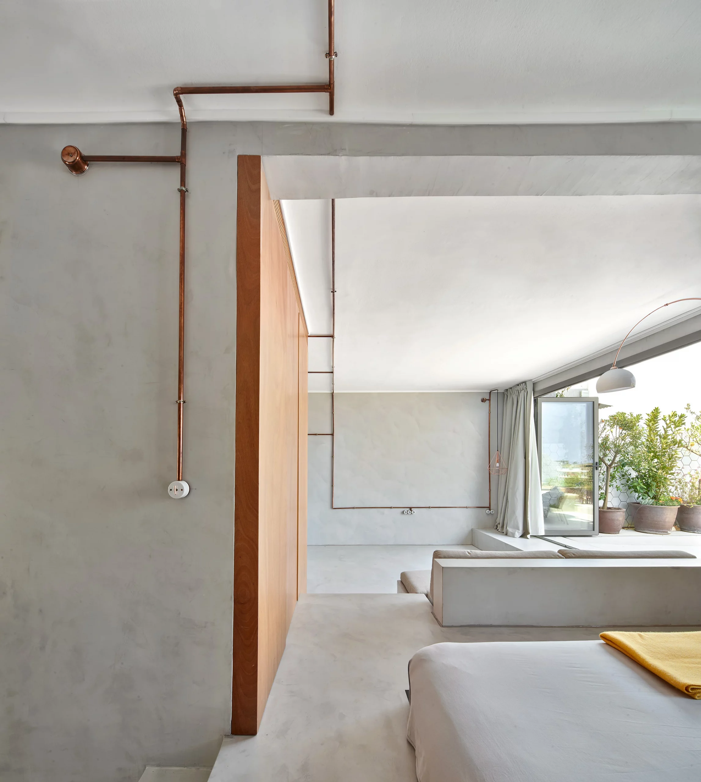 Interior of Marina Apartment showing bedroom, living area, and copper piping installations by Cometa Architects in Barcelona