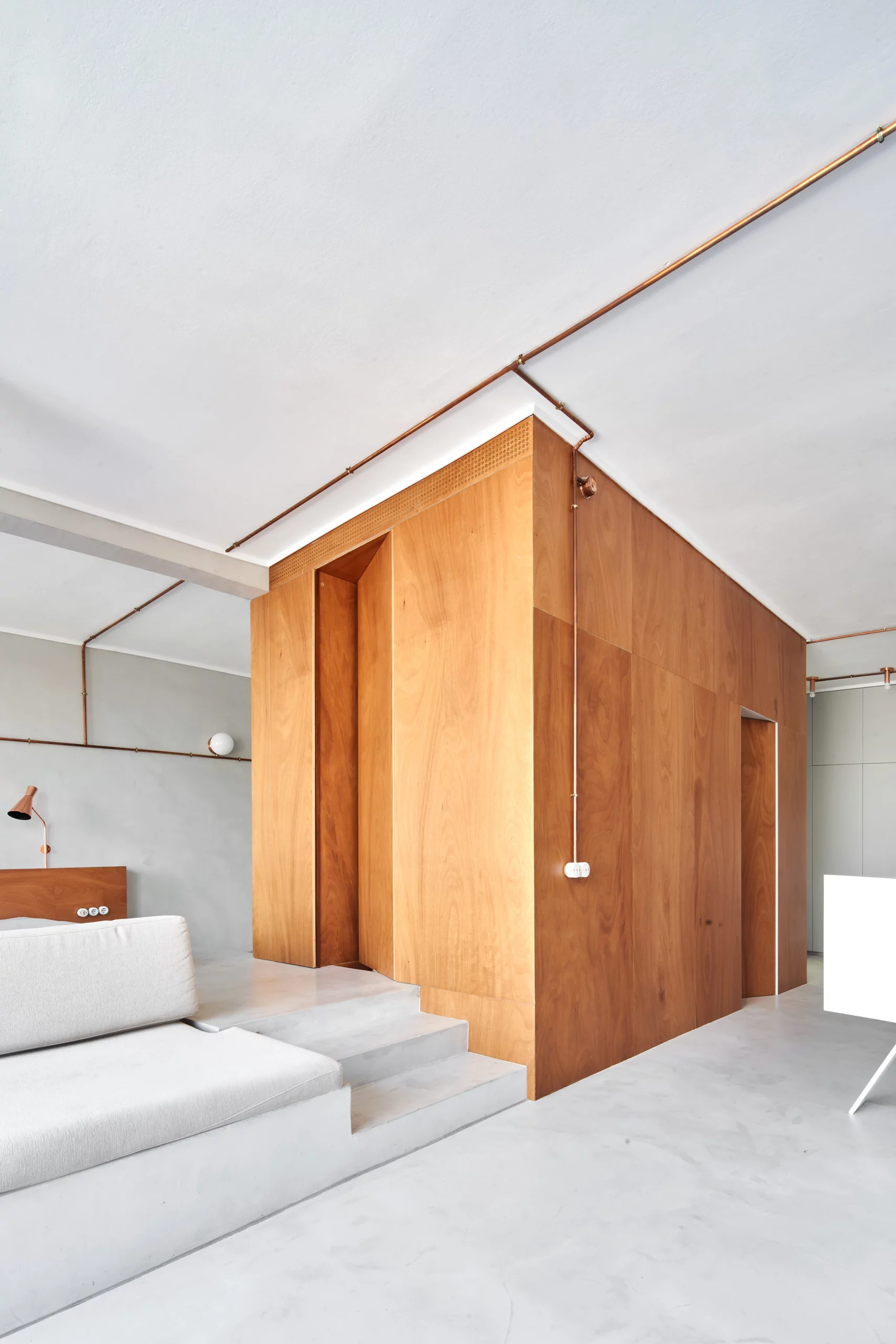 Interior view of Marina Apartment showing wooden central volume and copper piping by Cometa Architects in Barcelona