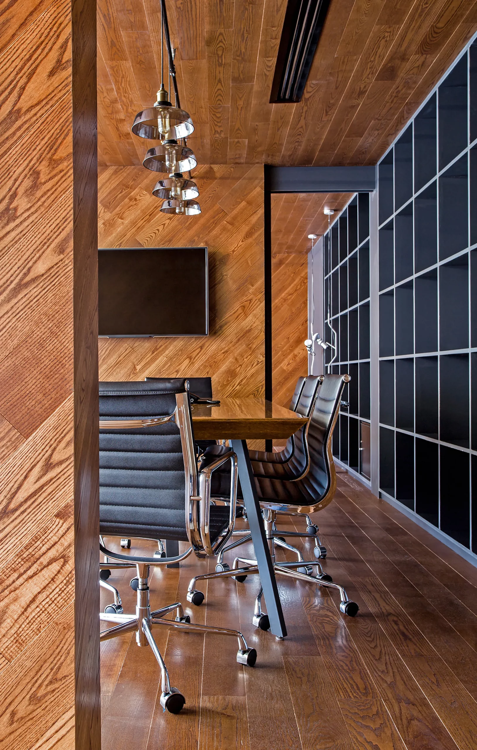 meeting room with custom wooden table, shelving grid and pendant lights at bpo office shanghai by cometa architects