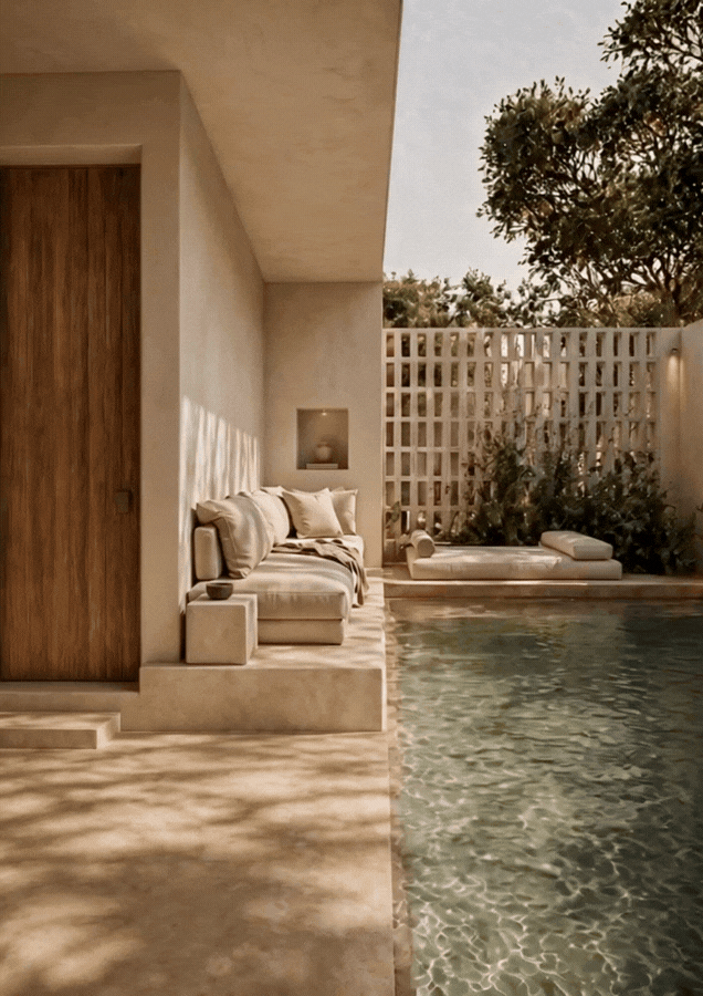 Pool lounge at Sa Capçada in Mallorca showing a shaded seating area, salt-water pool, timber door, lime-toned walls, Mediterranean planting and soft water reflections.